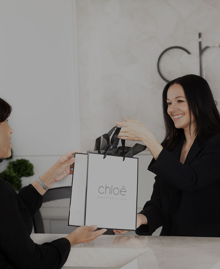Medical receptionist Guylaine Lavoie giving a Clinique Chloé gift bag to a patient