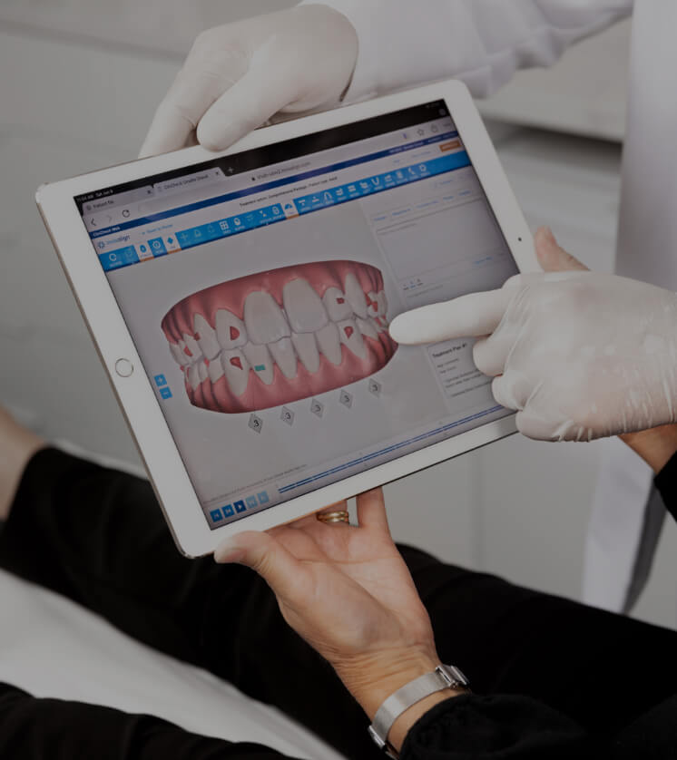 Le dentiste de la Clinique Chloé montrant une simulation Invisalign à sa patiente sur un iPad