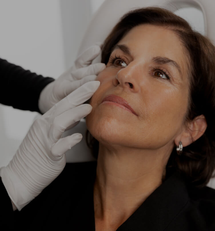 A medico-aesthetic technician from Clinique Chloé performing a visual examination of a patient's acne symptoms