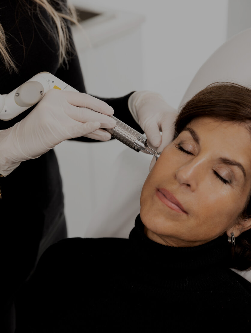 A medico-aesthetic technician from Clinique Chloé treating the face of a patient with the fractional laser