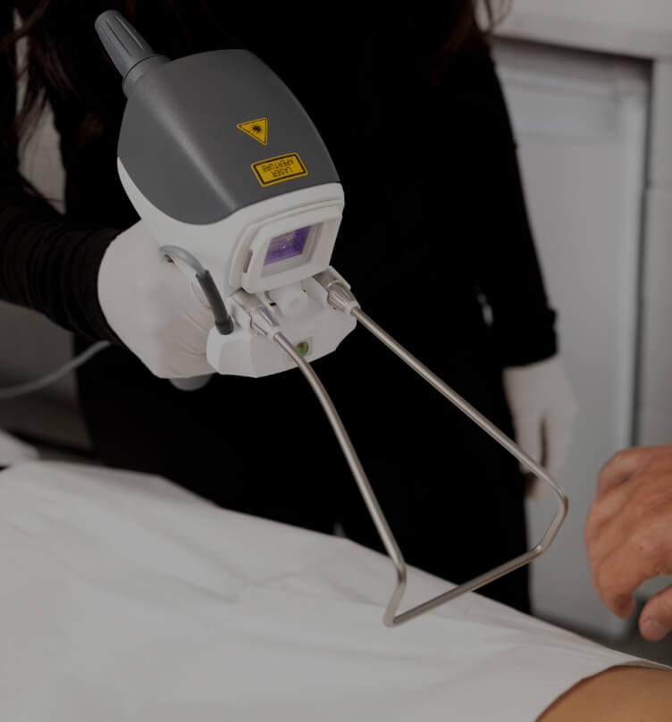 A medico-aesthetic technician from Clinique Chloé holding the Hot Sculpting laser handpiece in front of a patient