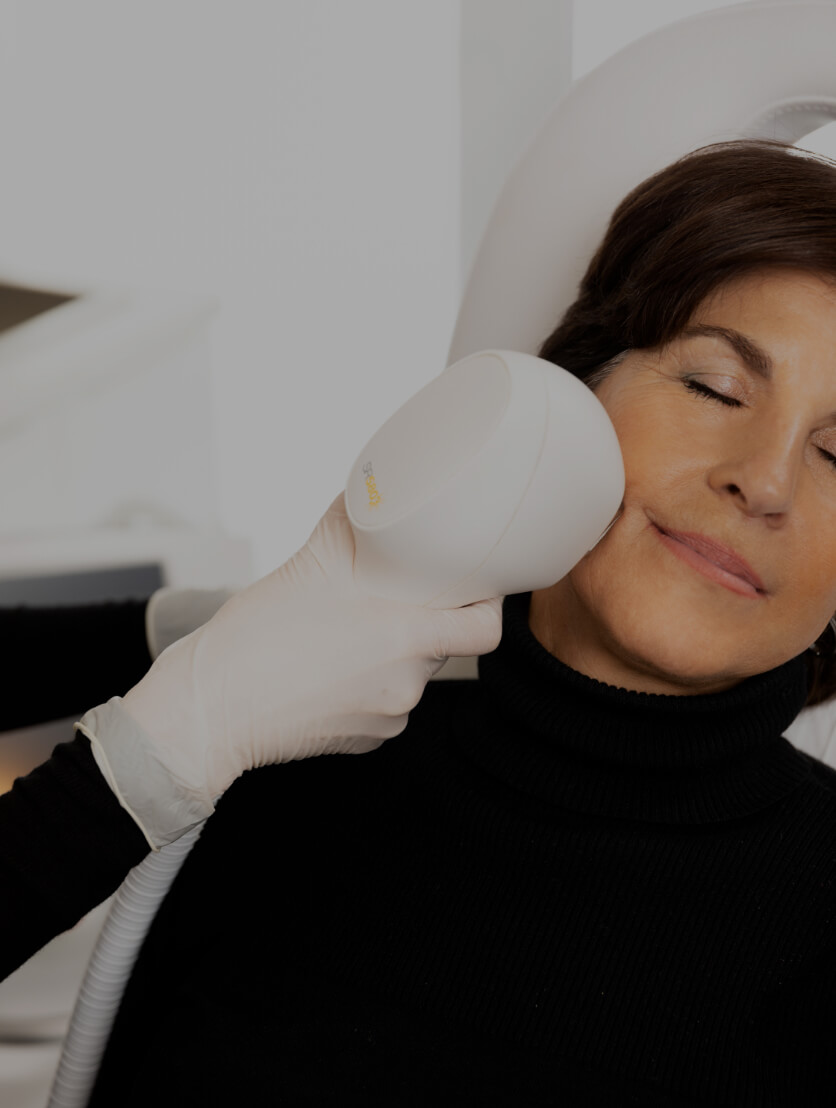 Une technicienne de la Clinique Chloé traitant le visage d'une patiente à l'aide d'un appareil de lumière intense pulsée