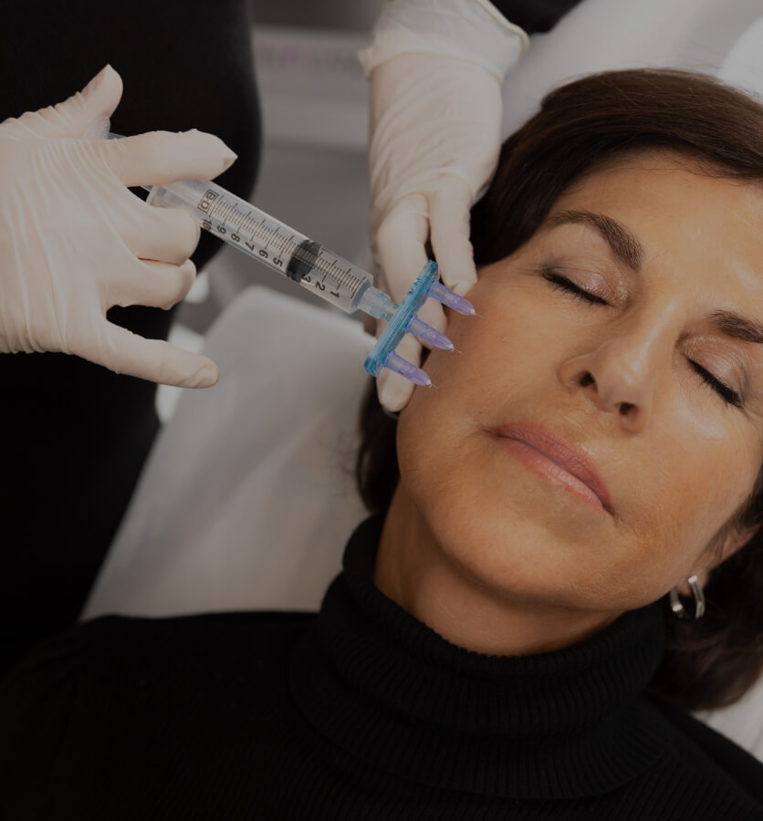 A nurse at Clinique Chloé performing local anesthesia on her patient's face using a multiport injector