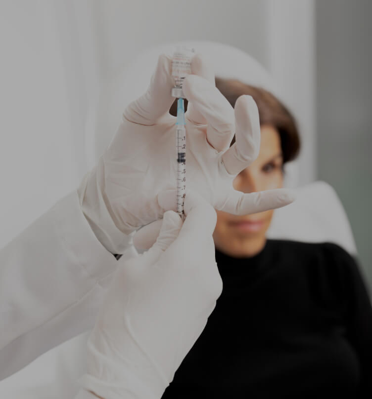 A doctor at Clinique Chloé preparing a syringe of Belkyra before treatment on a female patient