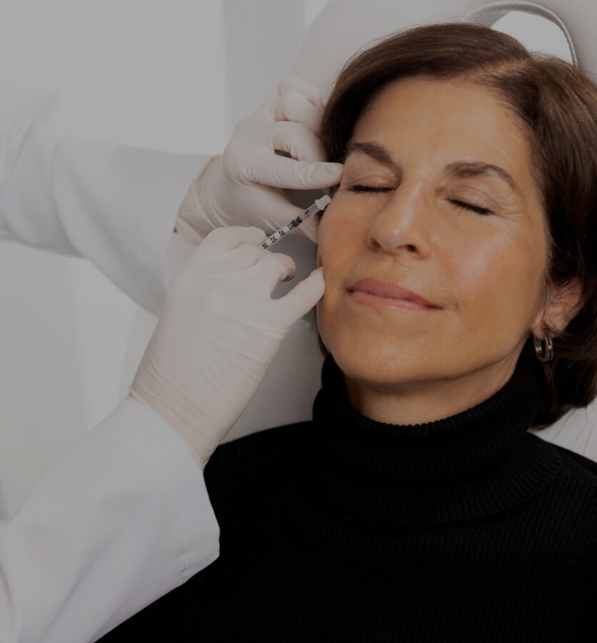 A doctor at Clinique Chloé treating a patient's crow's feet with neuromodulator injections like Botox